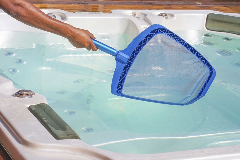 Person som rengör en bubbelpool med en håv