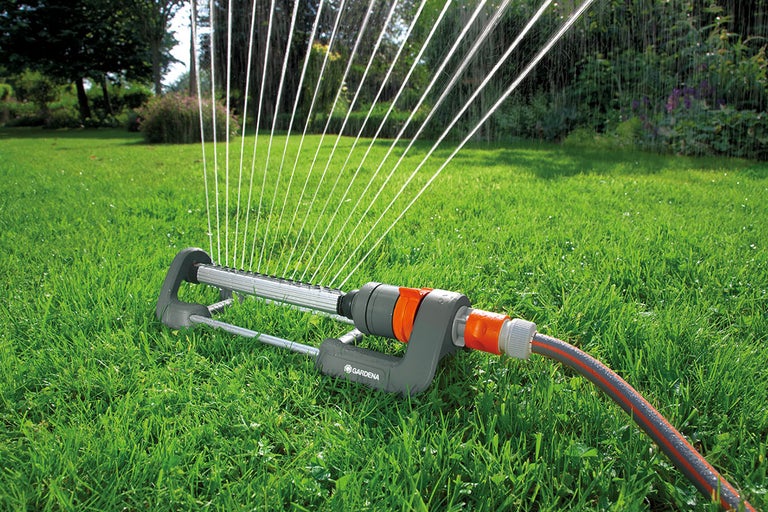 Grässpridare som vattnar en gräsmatta.