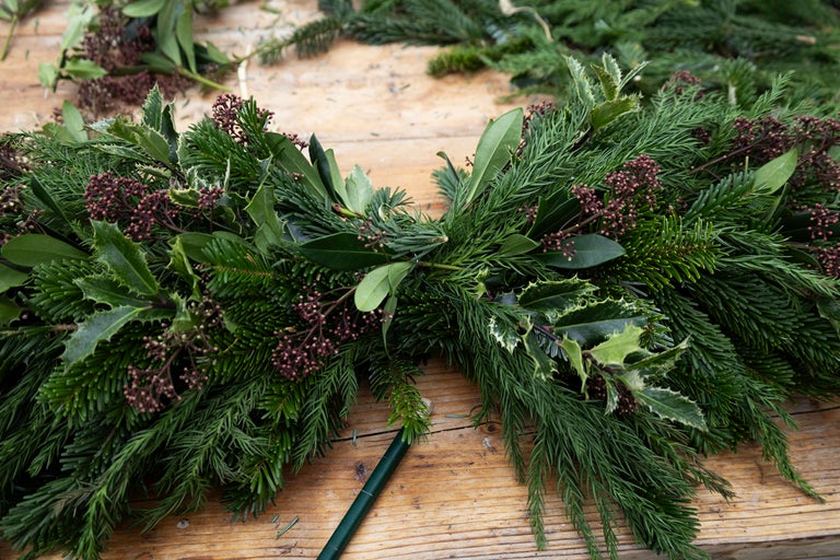 Dekorativ krans med grangrenar, järnek och bär på träbord