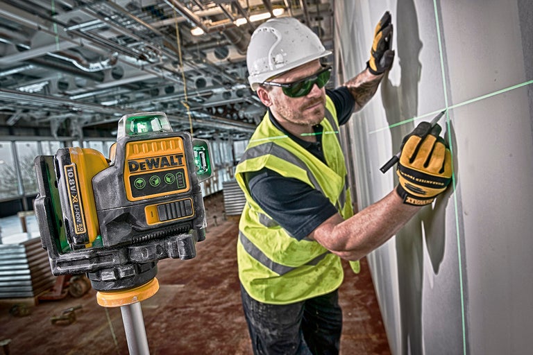 Dewalt korslinjelaser som används på en byggarbetsplats med en arbetare som gör markeringar på en vägg.