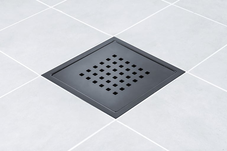 Fyrkantigt golvavlopp i metall med fyrkantiga hål på plattor