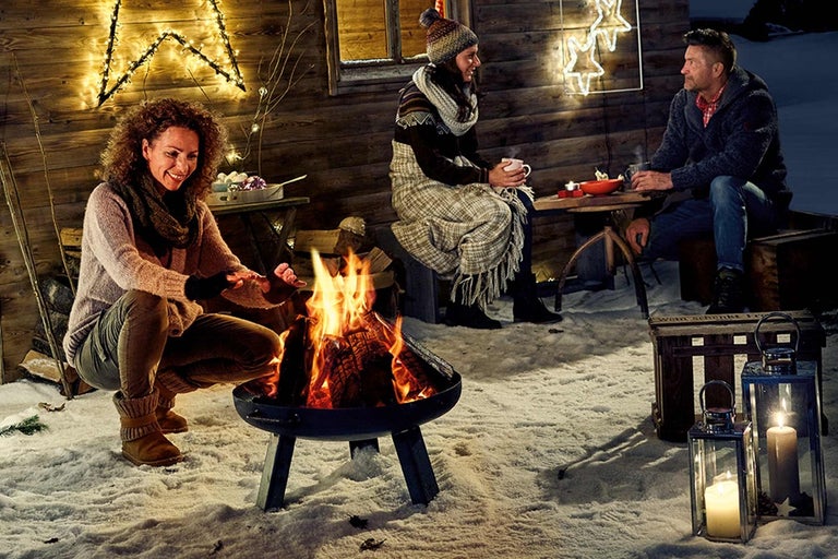 Människor sitter runt en eldstad i snön på vintern