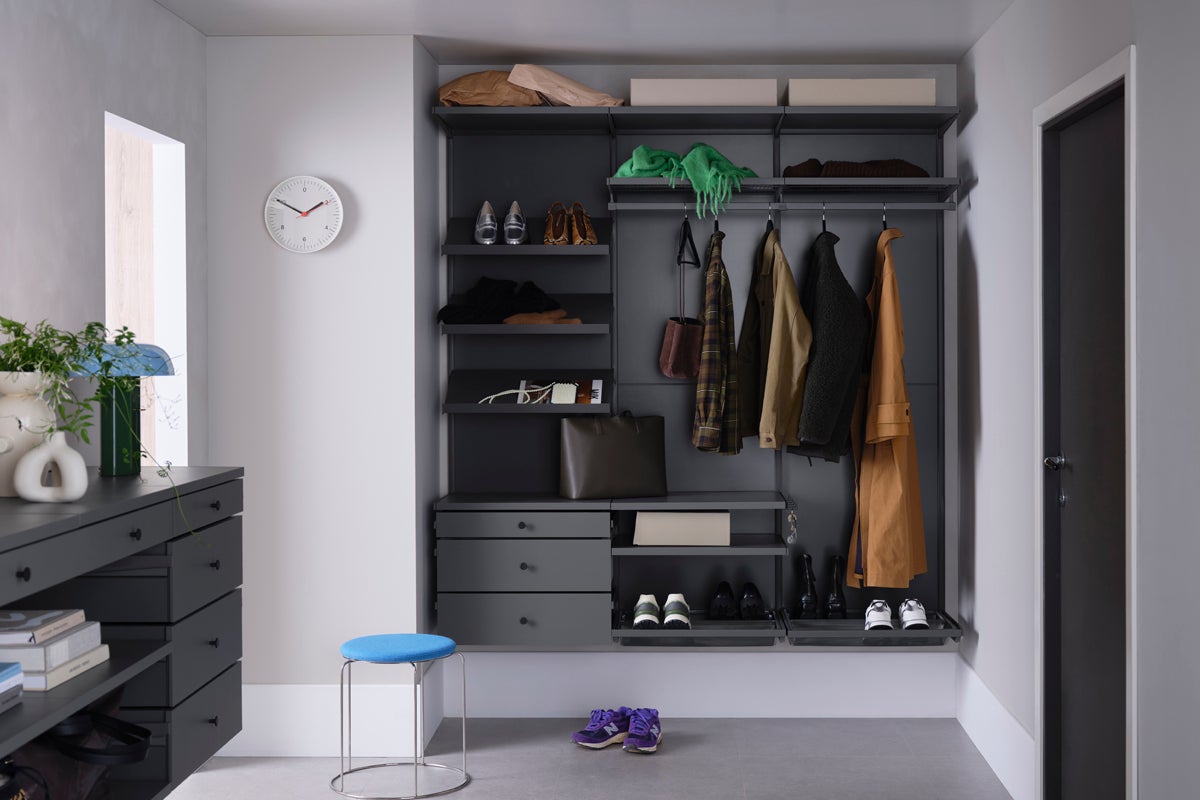 Klädkammare med hyllor, lådor och hängande kläder i ett ljust rum