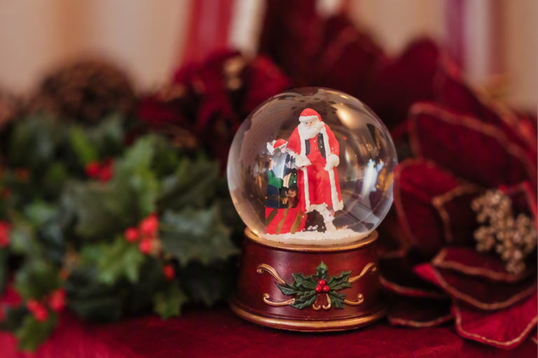 Snöglob med jultomtefigur på en dekorerad bas som festlig juldekoration.