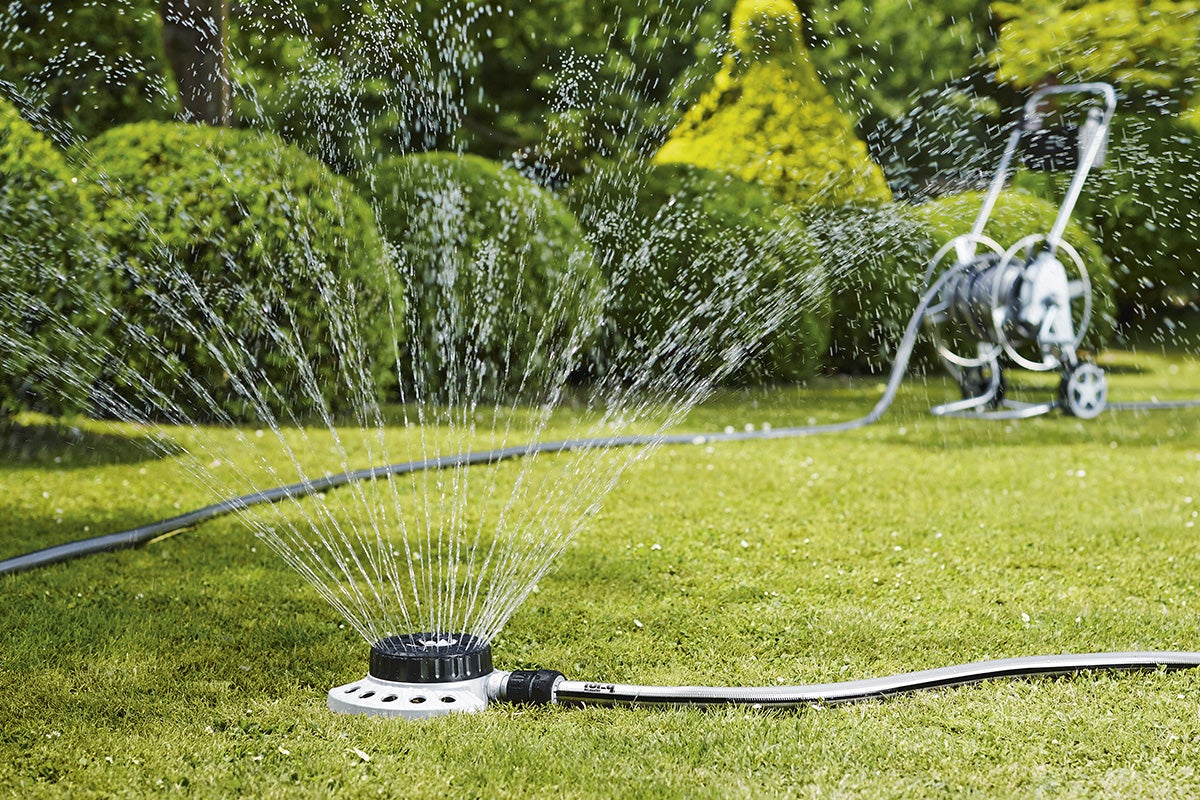 Grässpridare i drift på en grön gräsmatta