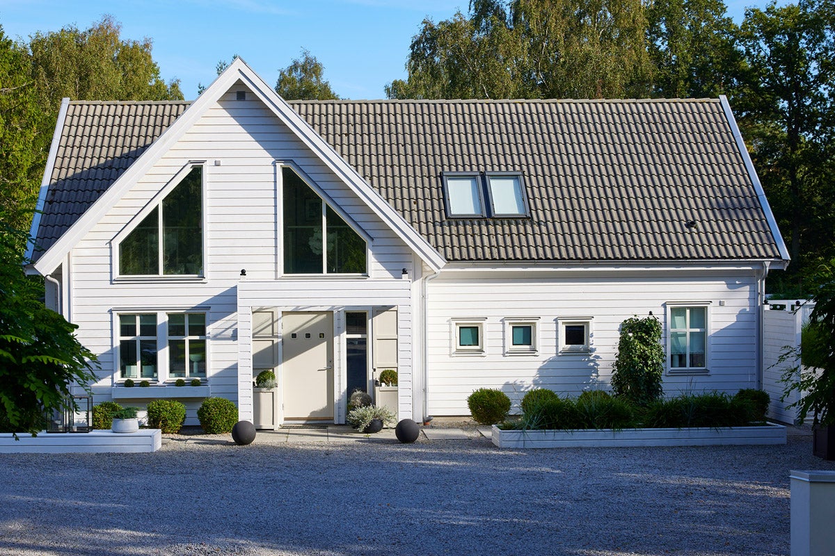 Modernt enfamiljshus med sadeltak, takfönster och välskött trädgård.
