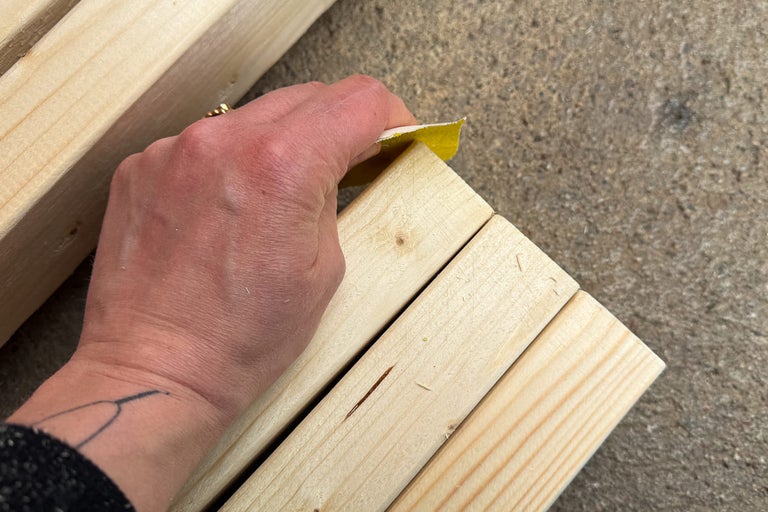 En person slipar trä med sandpapper