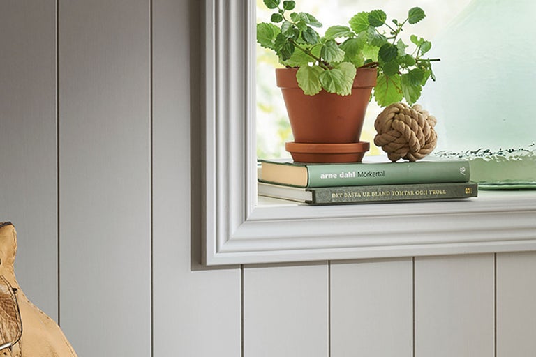 Dekorativ fönsterbräda med krukväxt, böcker och knutdekoration