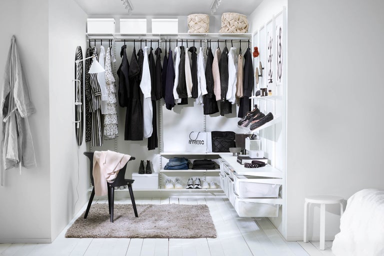 Klädkammare med kläder, skor och förvaringslådor i ett ljust rum