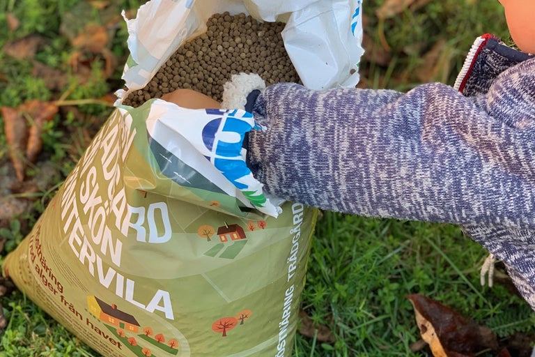 Öppen förpackning med trädgårdspellets på gräsmatta