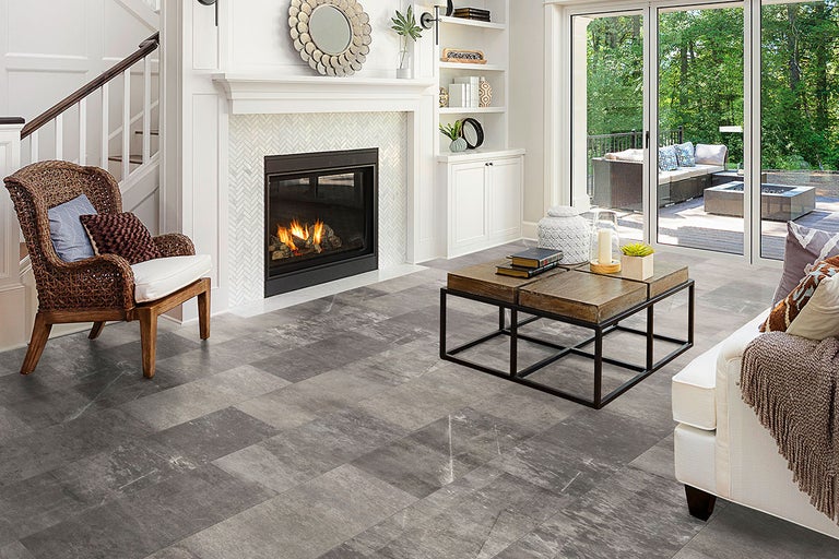 Vardagsrum med grått golv i kakeldesign, öppen spis och sittgrupp