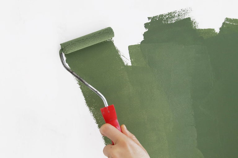 En person målar en vägg med en färgrulle