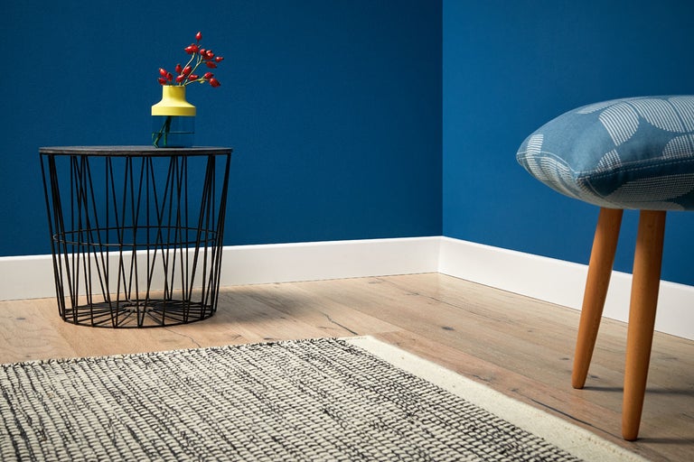 Inredningsexempel: vardagsrum med sidobord, dekoration och pall framför en blå vägg