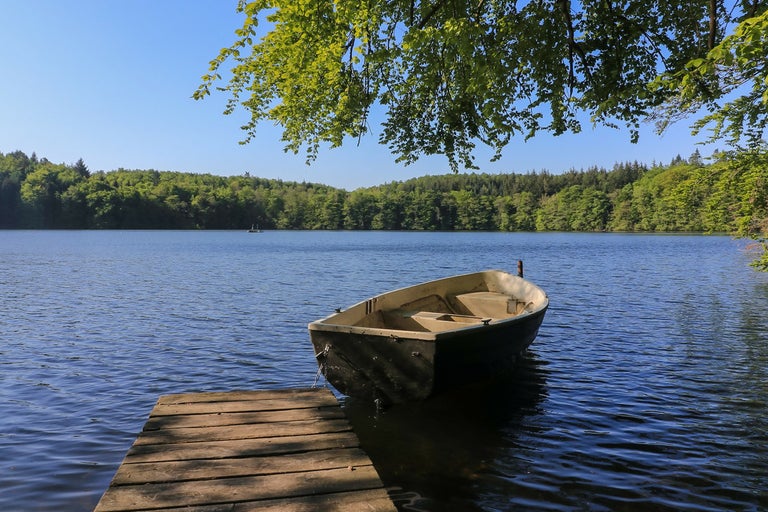 Roddbåt vid sjön vid en brygga av trä