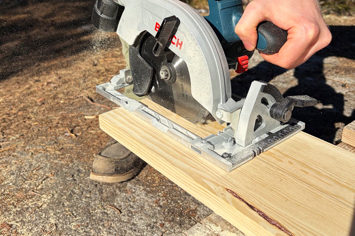 Bosch cirkelsåg sågar en träplanka med flygande sågspån.