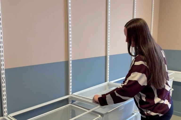 Kvinna monterar ett hyllsystem med lådor