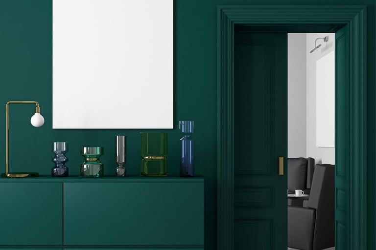 Interiörvy med byrå, dekorativa vaser, lampa, dörr och tom affisch