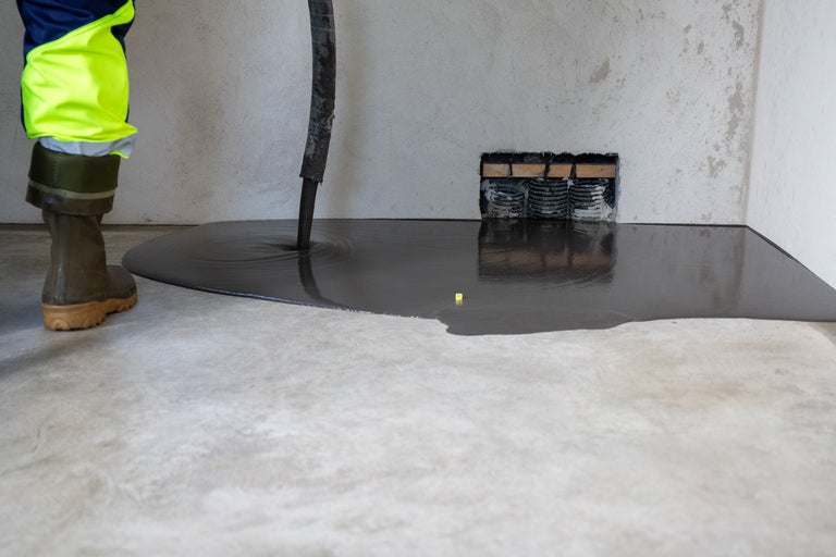Arbete med avjämningsmassa inomhus med en arbetare och en slang