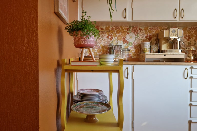 Köksscen med gul hylla, porslin, krukväxt och köksmaskiner