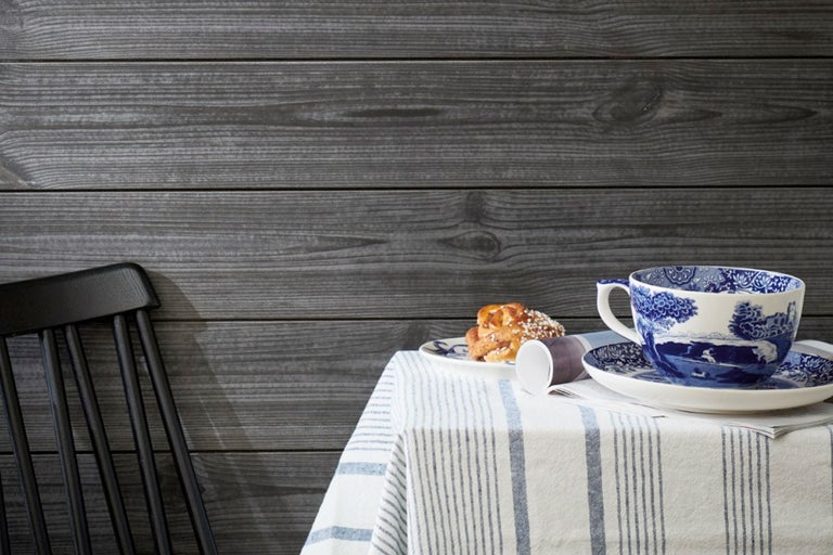 Miljöbild med trävägg, stol, dukat bord med bakverk och porslin