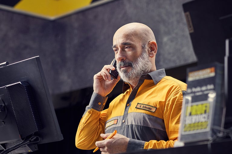 En Hornbach-anställd talar i telefon vid disken i butiken.