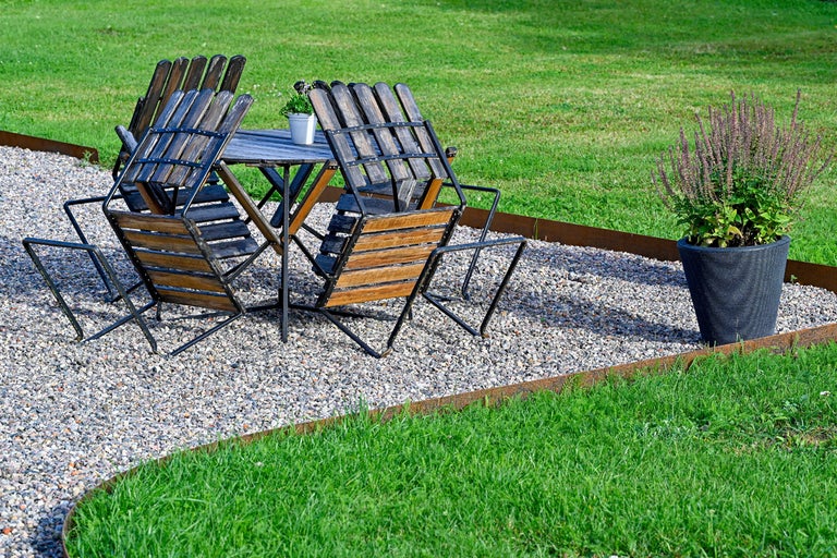 Trädgårdsscen med trädgårdsbord, trädgårdsstolar och blomkruka