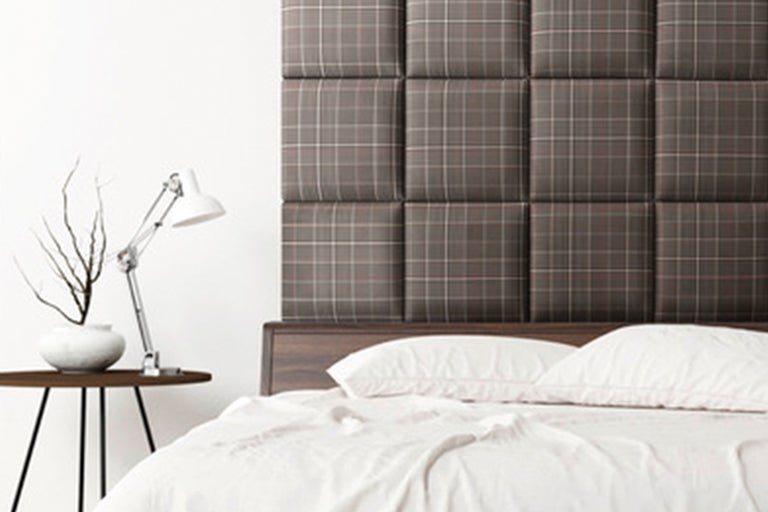 Sovrum med säng, sänglampa och vadderad sänggavel