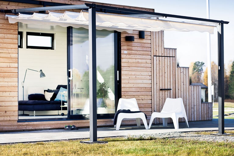 Utomhusvy av ett hus med terrassöverdrag och trädgårdsmöbler