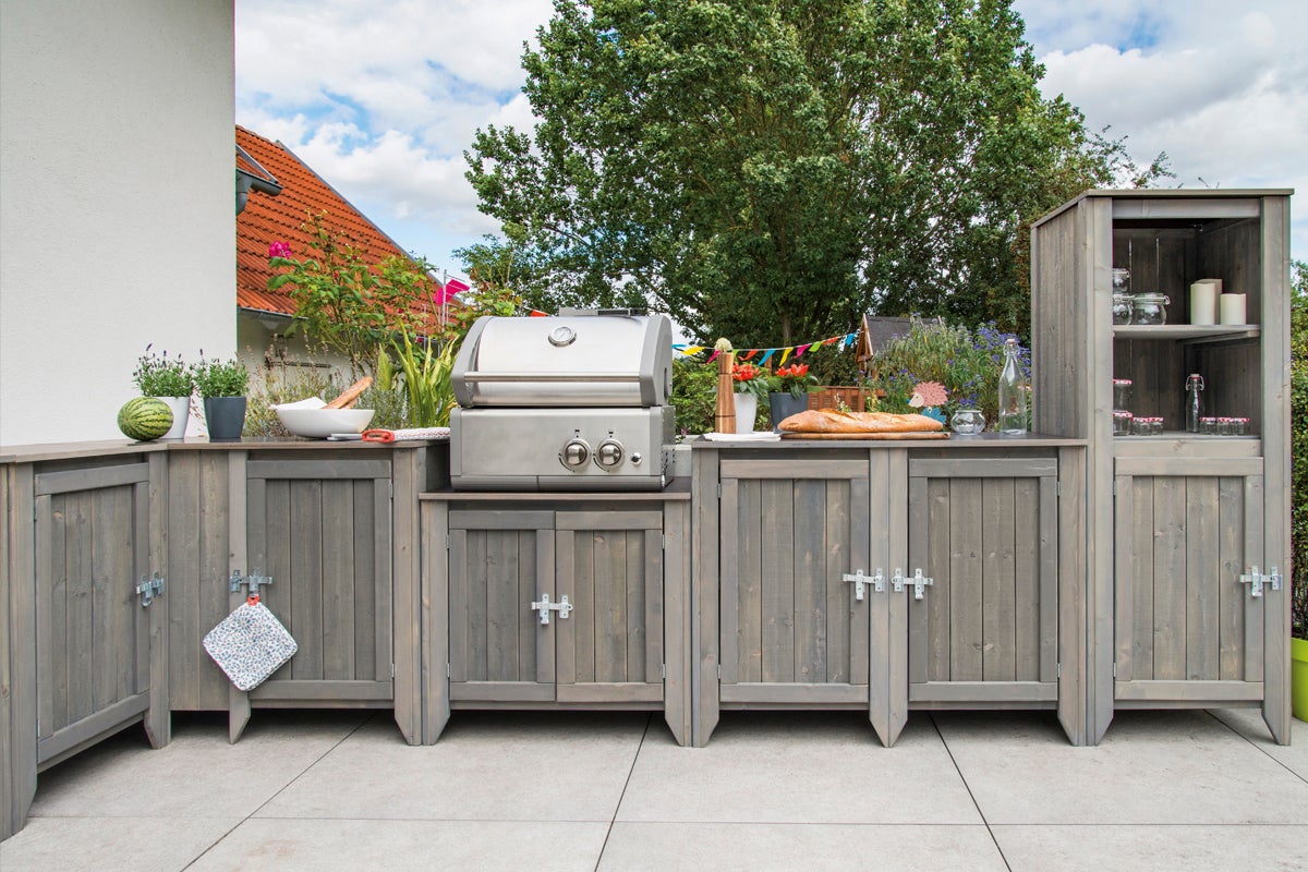 Utekök med grill, arbetsytor och förvaring på en terrass.