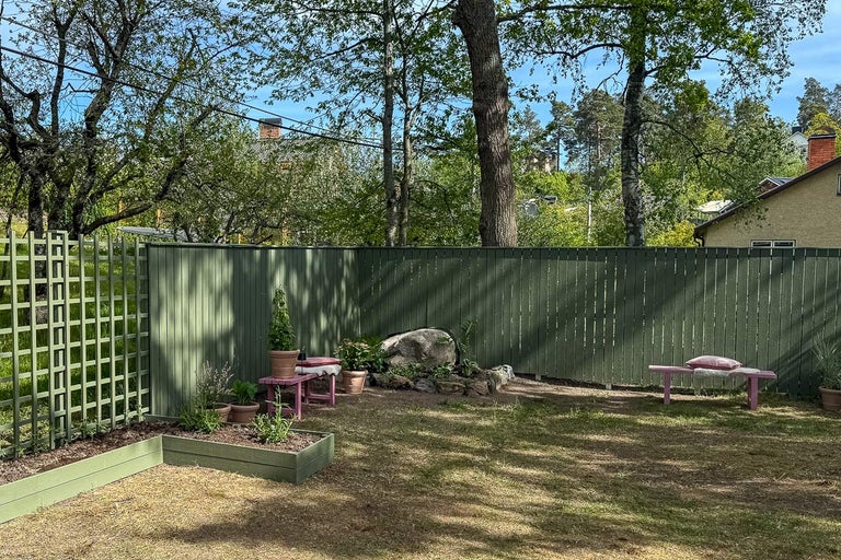 Trädgård med trästaket, upphöjd rabatt och sittplatser