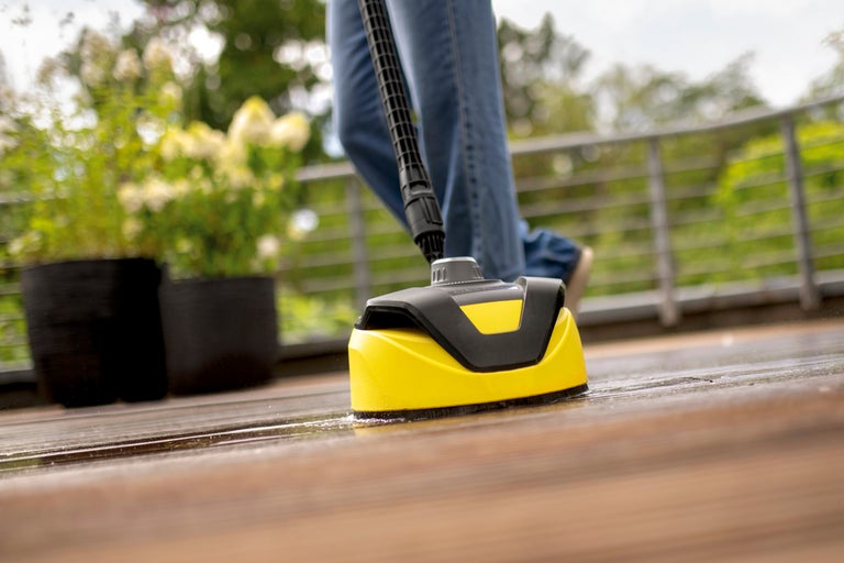 Gul altantvätt används på en träterrass. I bakgrunden syns växter i krukor och ett metallräcke.