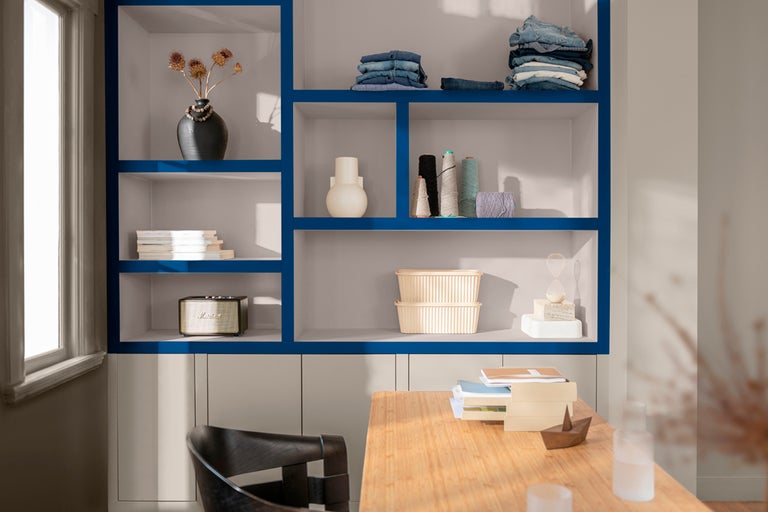 Hylla med dekorationer och bord i ett ljust rum