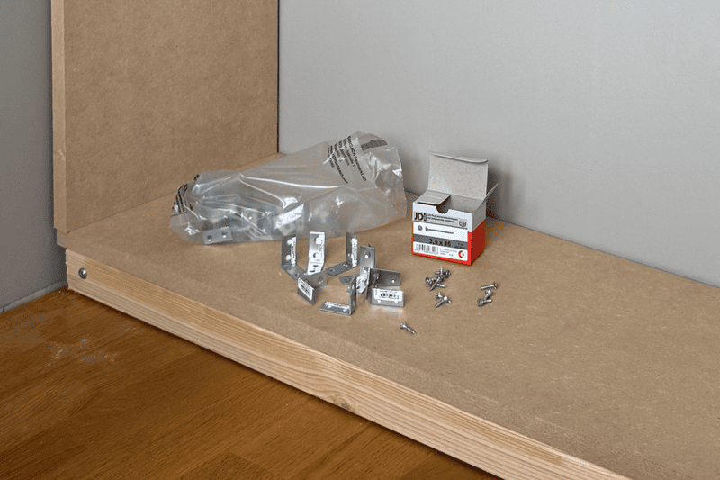 Hörnkontakter, skruvar och skruvpaket på en träyta