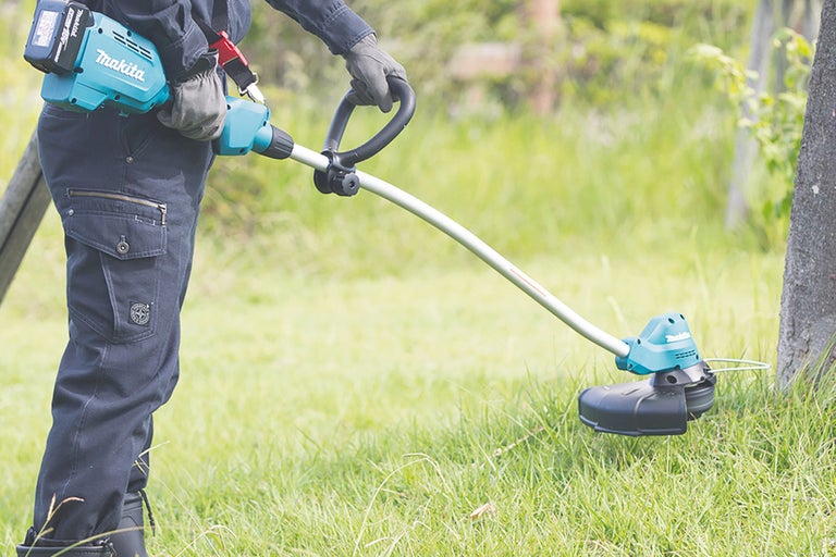 Batteridriven grästrimmer som används i trädgården