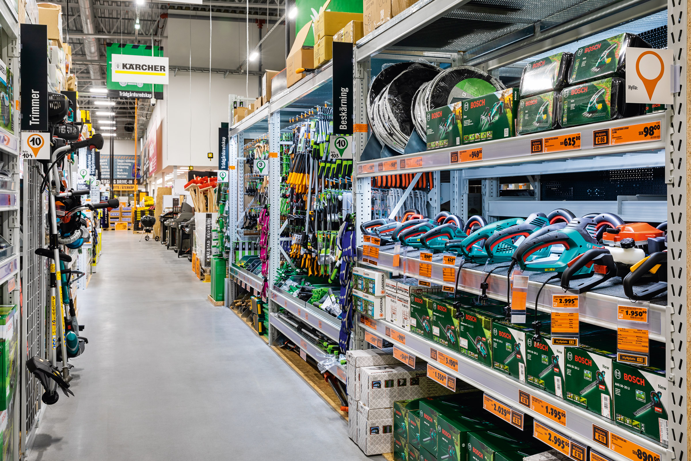 Gångvy i en Hornbach-butik med hyllor fulla av trädgårdsredskap som trimmare, häcksaxar och sekatörer från varumärkena Kärcher, Bosch och Gardena.
