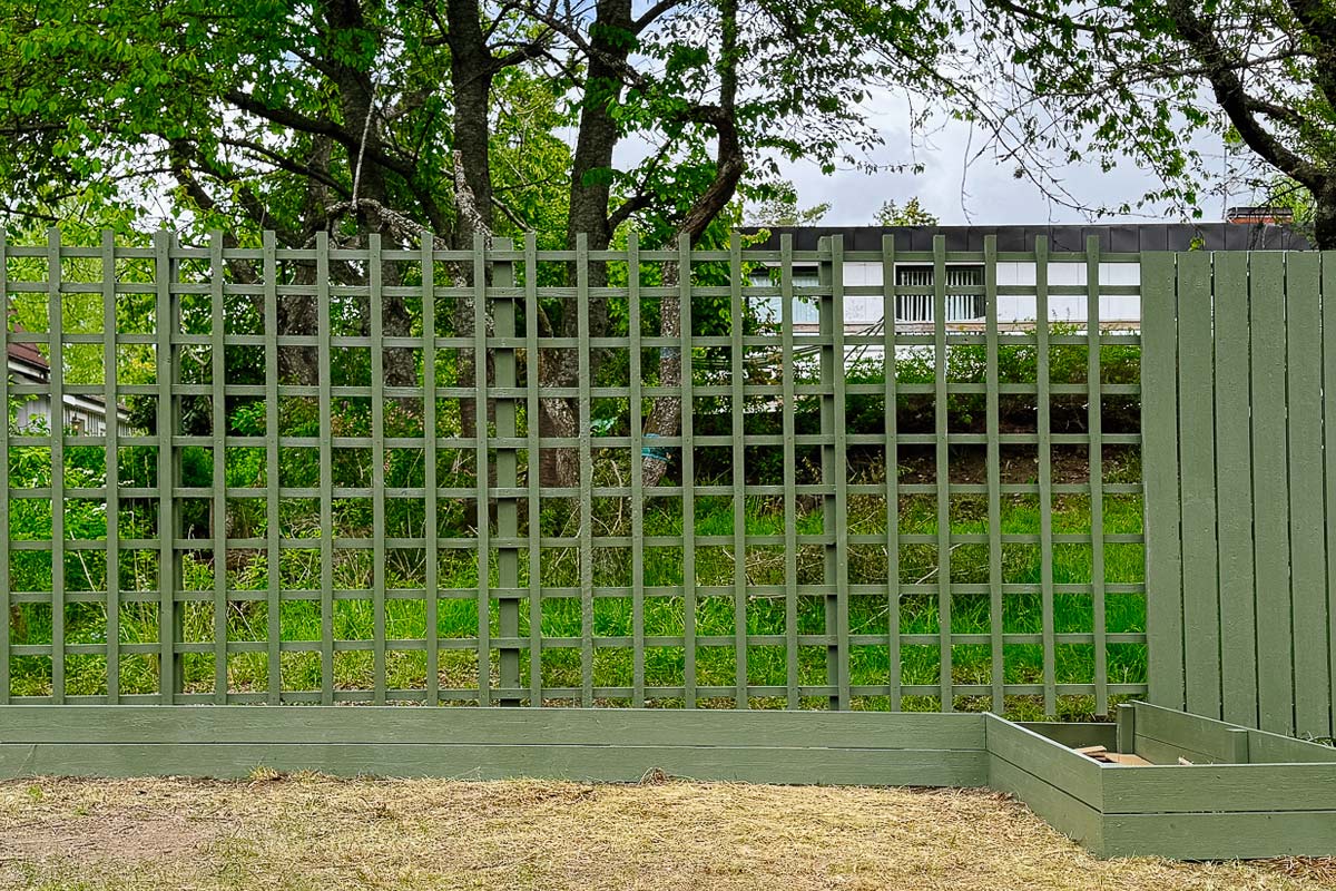 Trästaket med gallerstruktur och upphöjd rabatt i trädgården