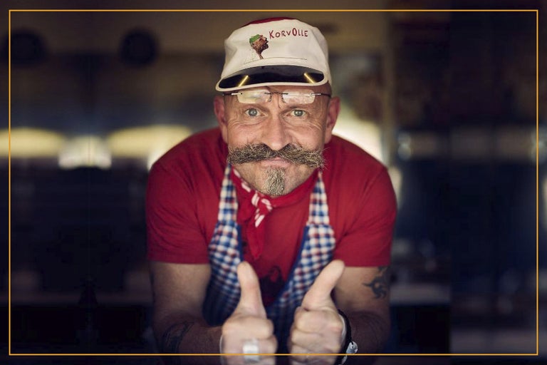 Man med skägg och keps med kockmotiv ger tummen upp