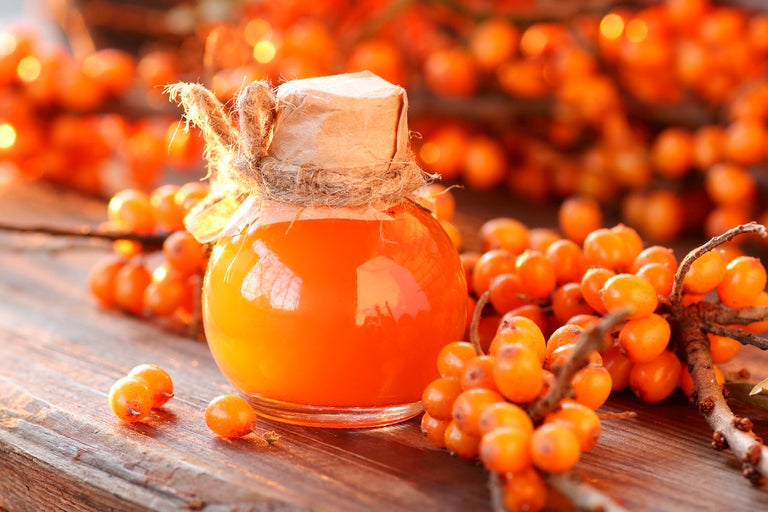 Havtornsmarmelad i glasburk med papper och snöre på träbord