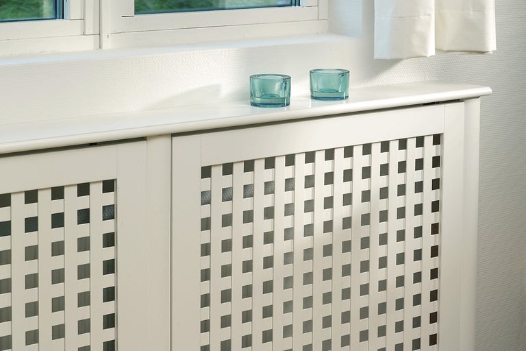 Radiatorkåpa under ett fönster med två värmeljus