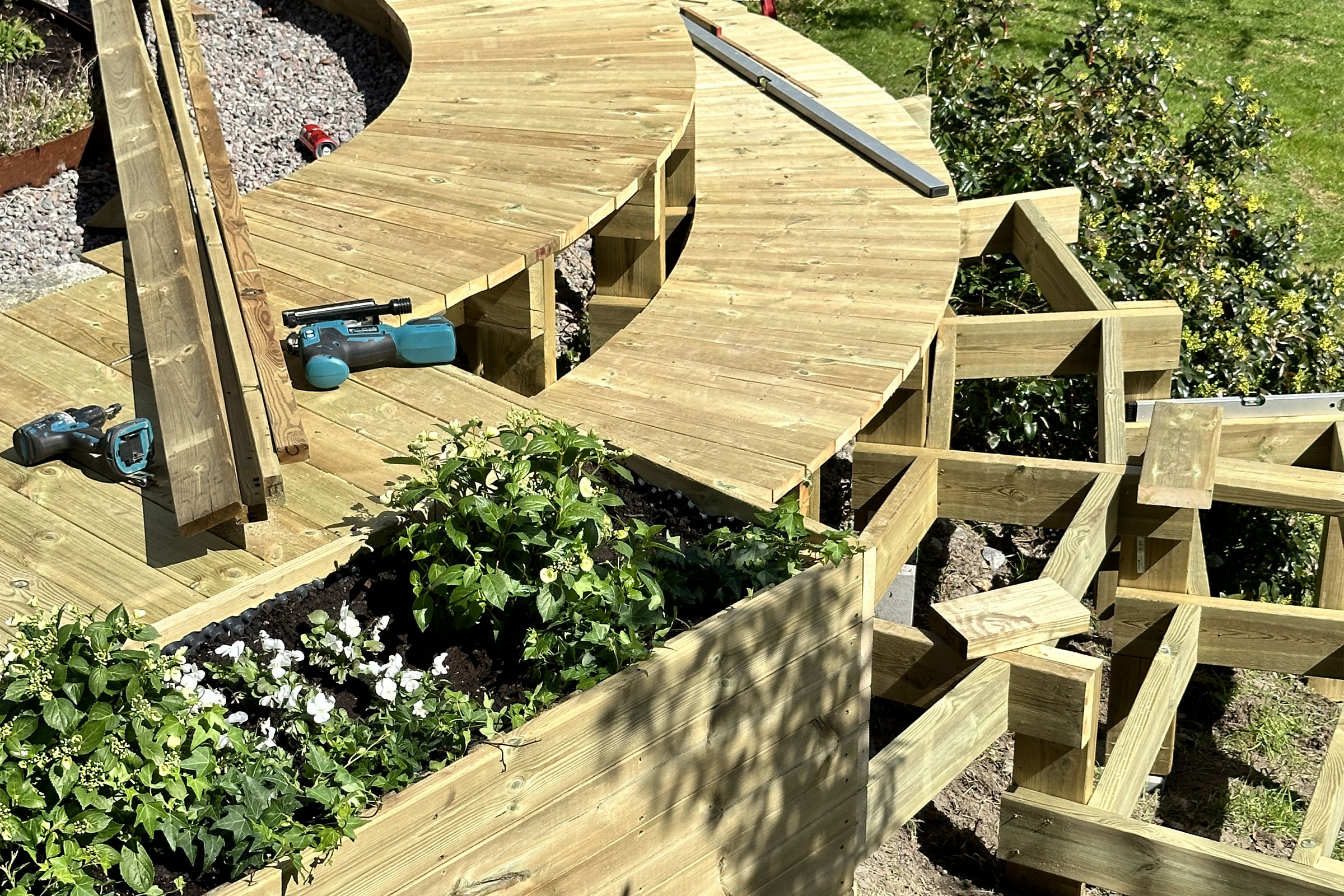 Träterrass under konstruktion med planteringslåda och verktyg