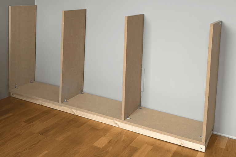 Råbyggnad av en träbokhylla med MDF-skivor mot en vägg