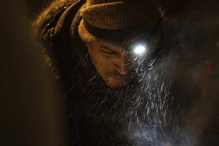 Man med pannlampa i snöfall