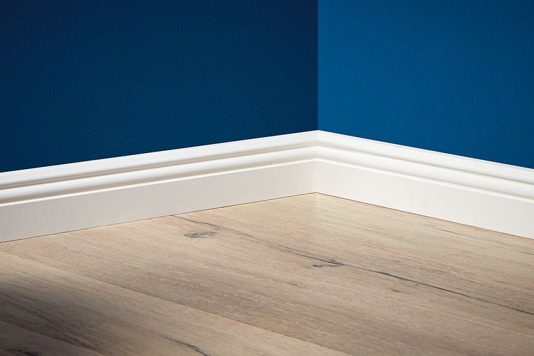 Innerhörn med golvlist, vägg och laminatgolv.