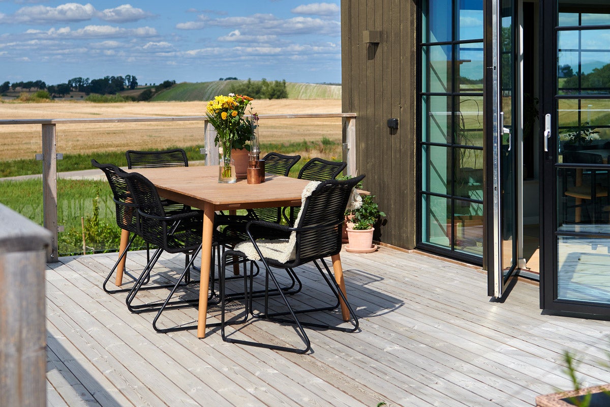 Uteplats med träbord och svarta stolar