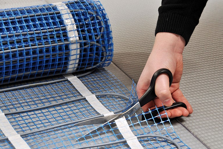 Klippa en elektrisk golvvärmematta med en sax