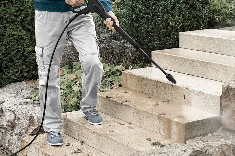 Person rengör stentrappa med högtryckstvätt