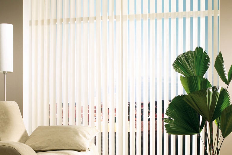 Vertikala persienner i vardagsrummet med soffa och krukväxt