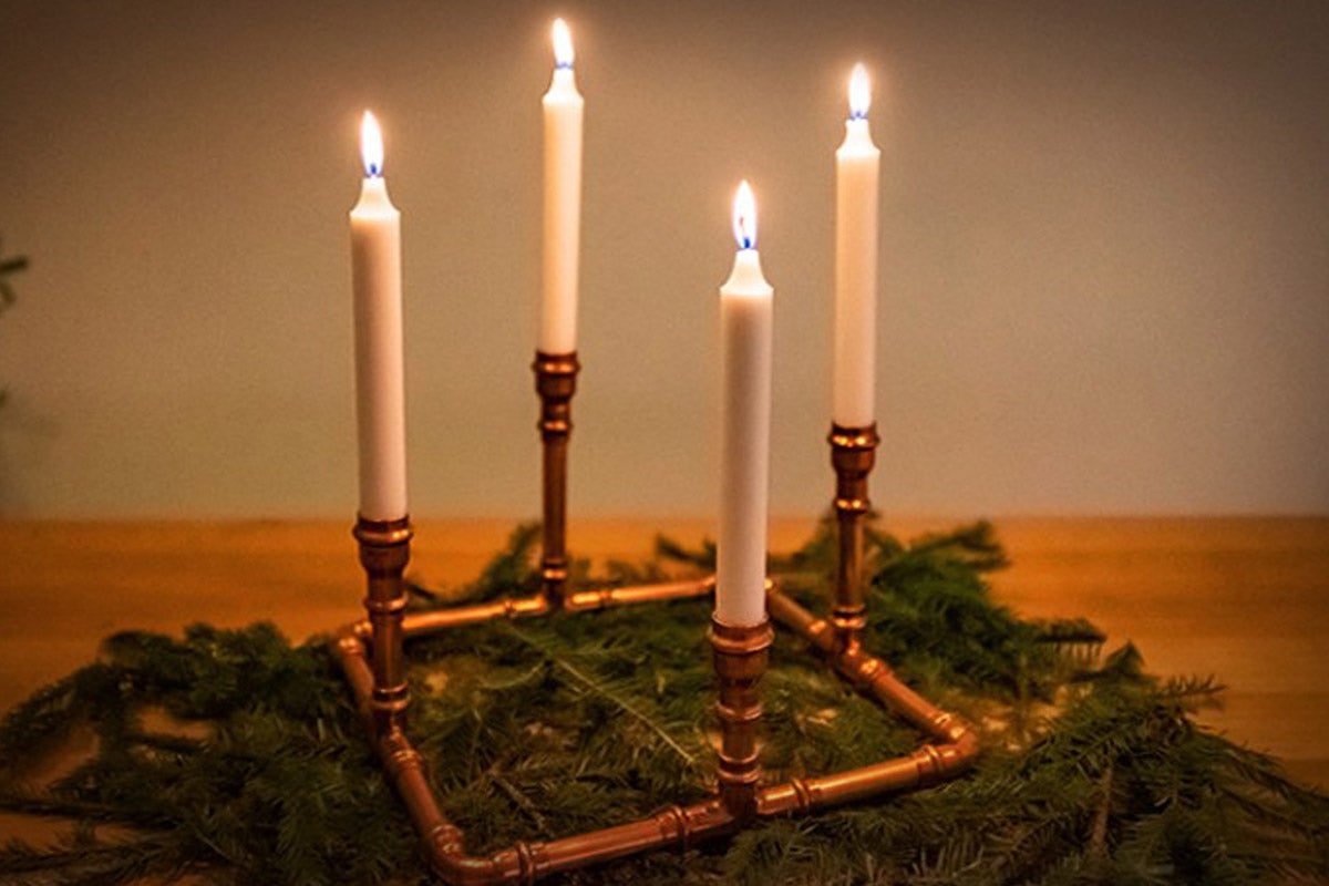 Adventskrans med fyra brinnande ljus på grangrenar