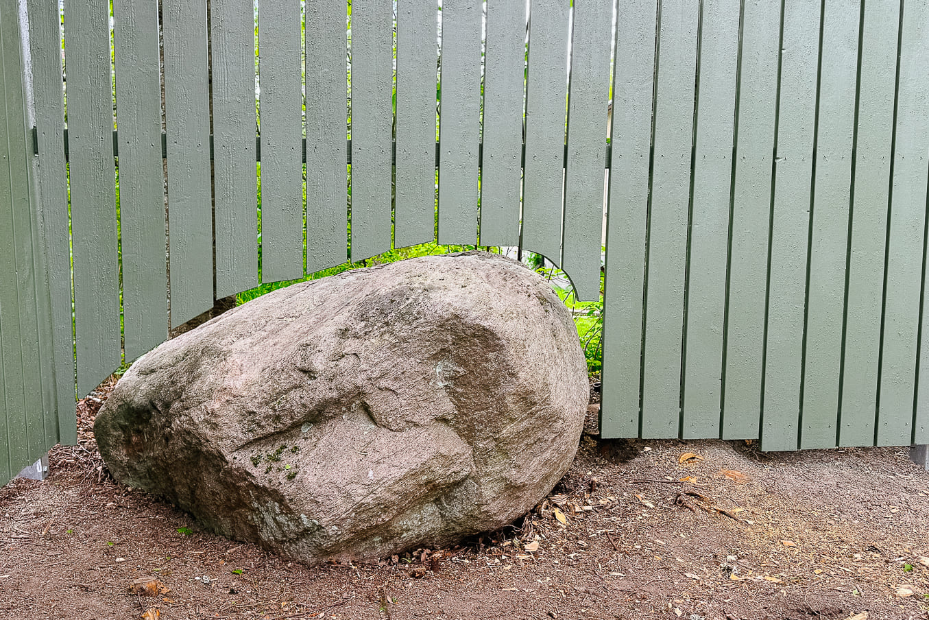 Trästaket med en stor sten