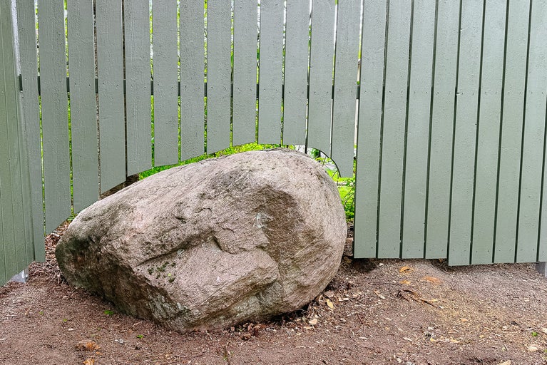 Trästaket med en stor sten